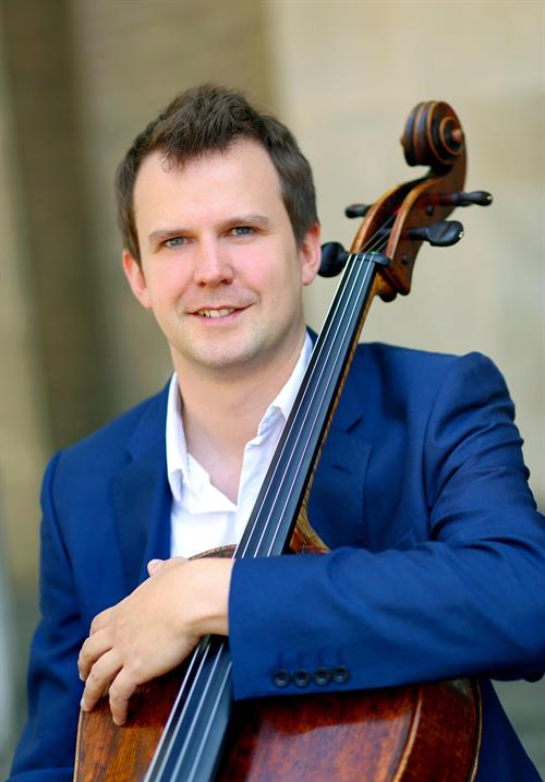 man in blue suit jacket holding a cello 
